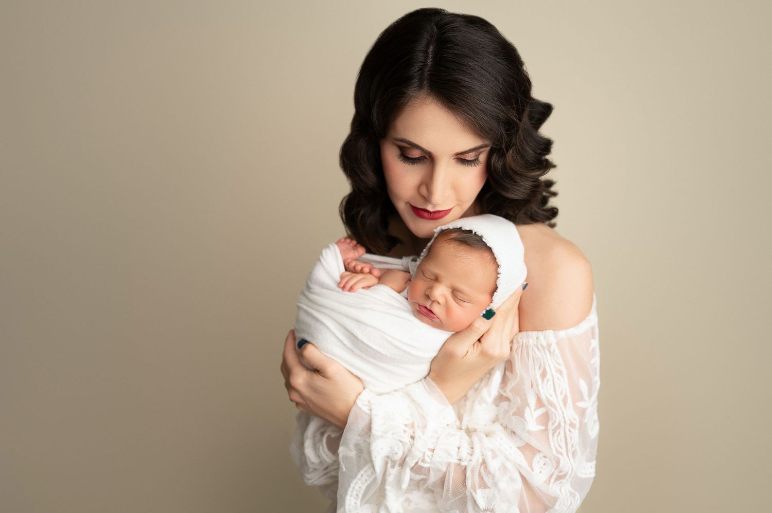 A woman in a white off-shoulder top poses gracefully with her swaddled newborn in Lemoore, CA.