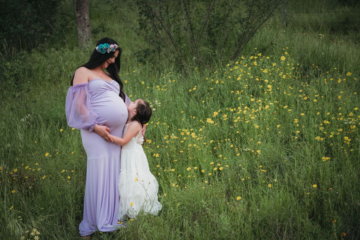 Two people embrace in a meadow filled with yellow wildflowers during a spring photoshoot. Fresno Family Photography