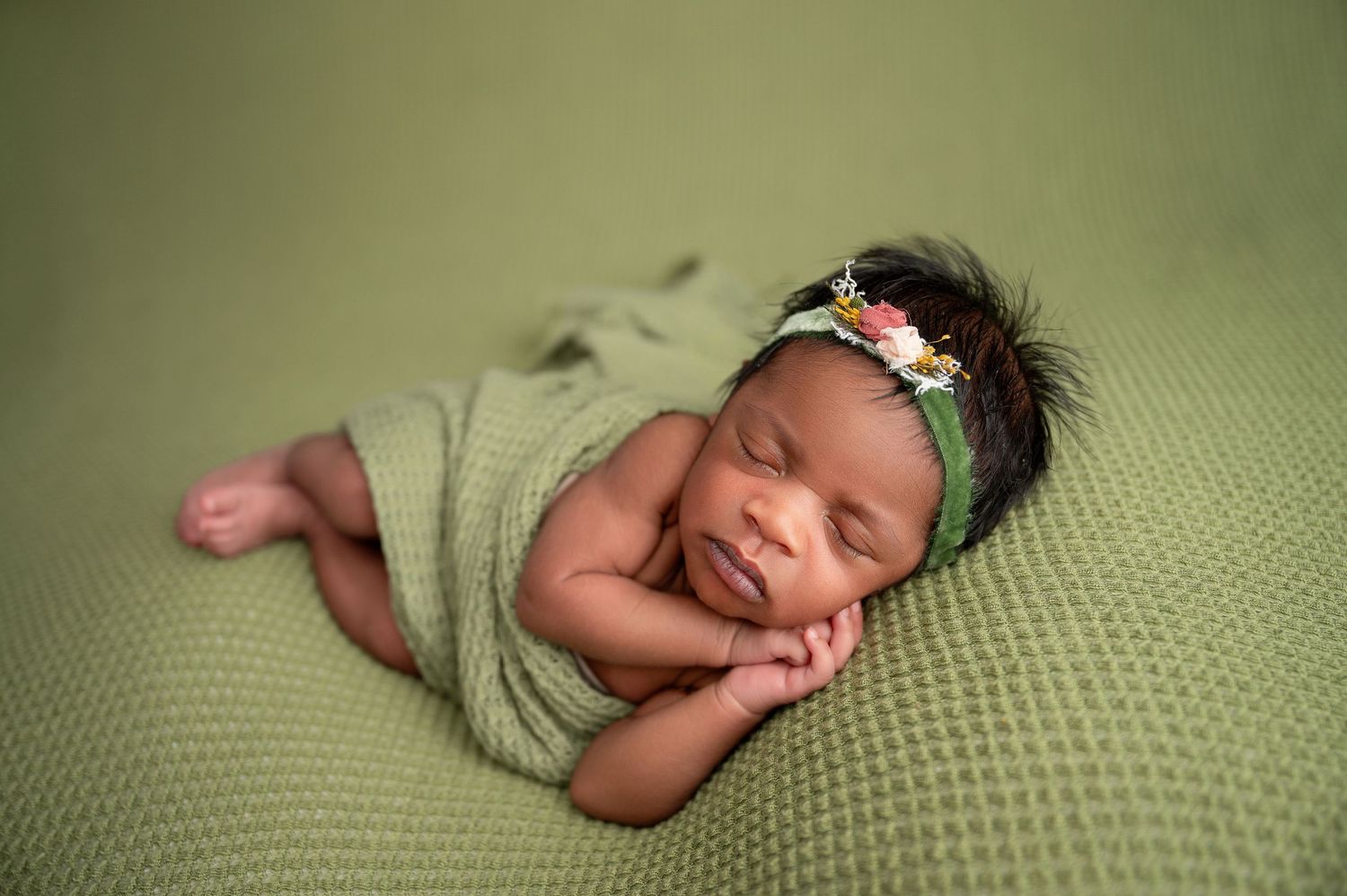 Professional newborn photo series on sage green textured backdrop.