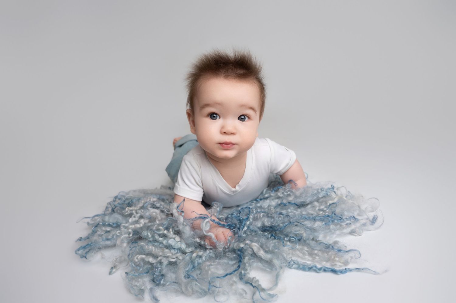 Baby milestone photos with soft blue textured fabric showing growth and development.