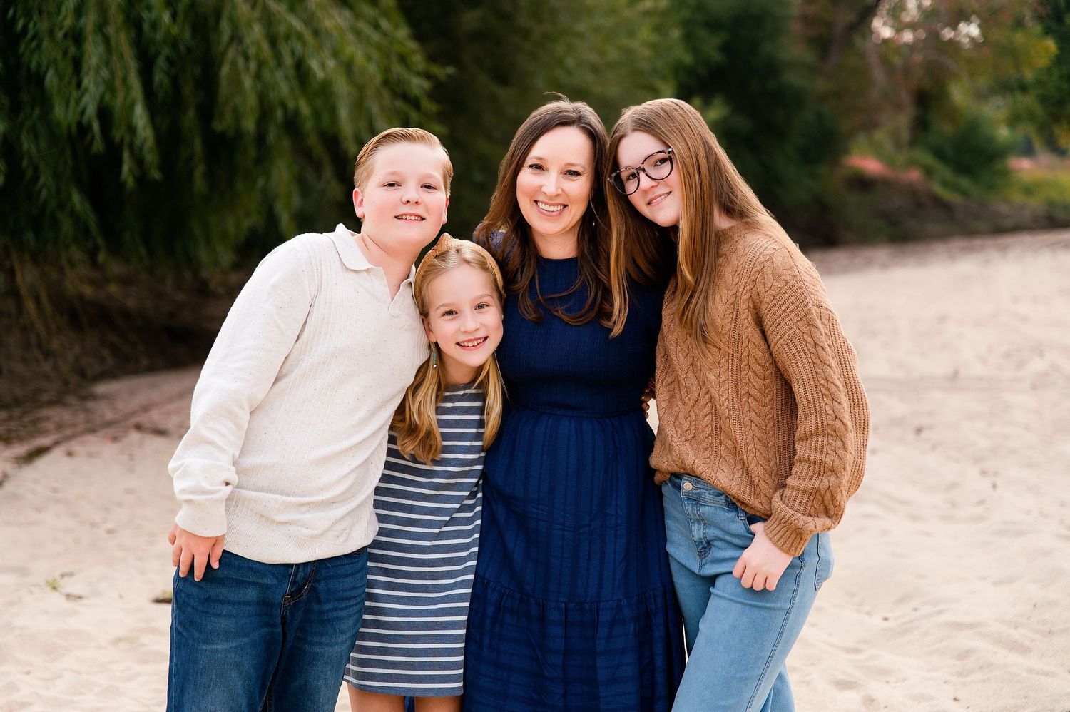 A group stands together outdoors in coordinating blue and white outfits against a natural backdrop. Fresno Family Photography