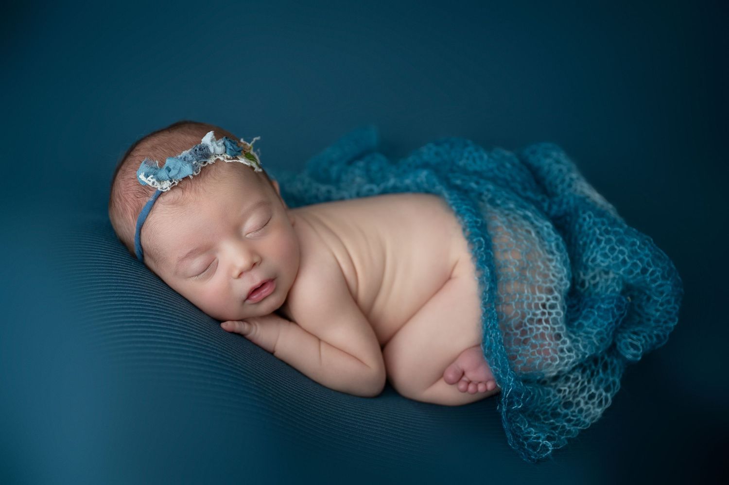 Serene newborn portraits with teal blue backdrop and matching knit accessories.