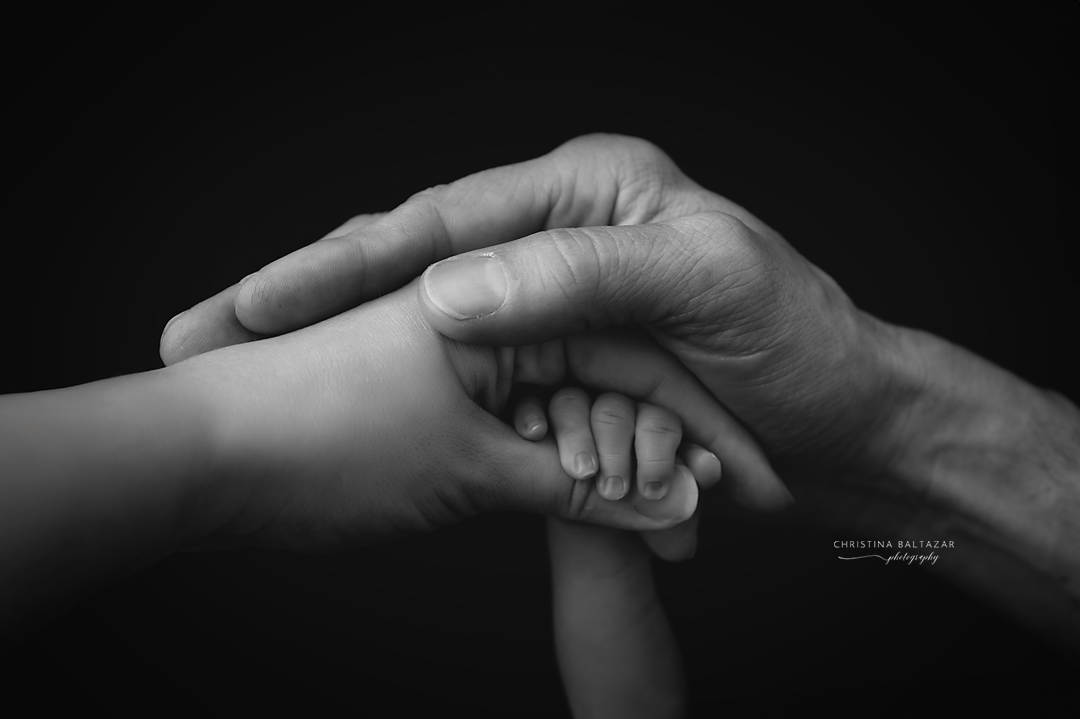 Black and white photo showing three generations holding hands together.