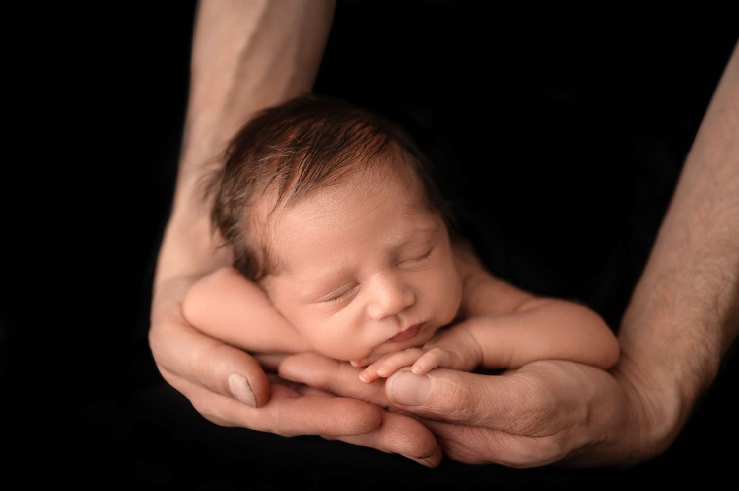 A series of black and white photographs showing a sleeping newborn baby cradled in gentle hands. Hanford Newborn Photographer