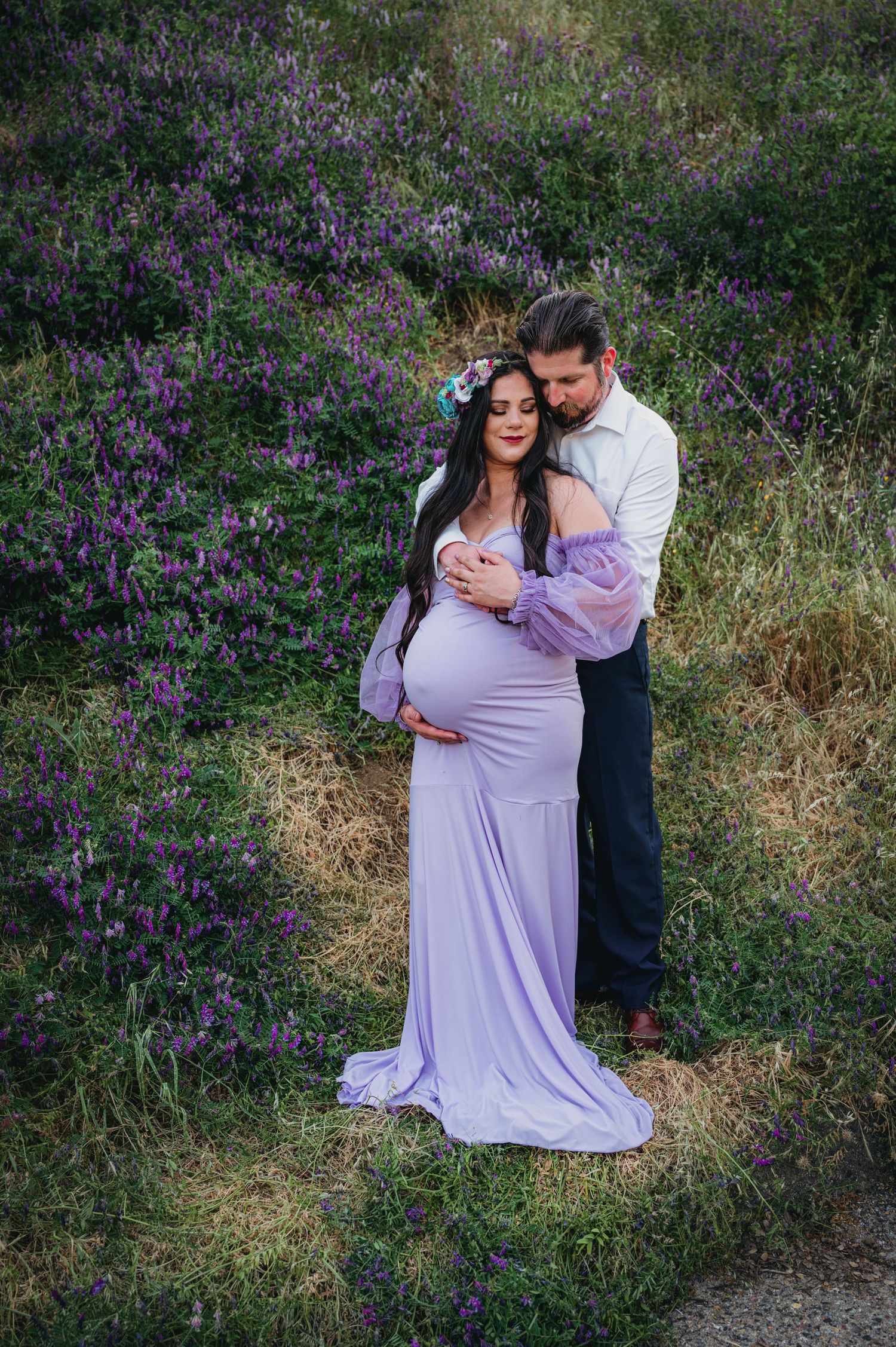 Couple embraces in purple wildflower field during maternity photoshoot. Hanford Maternity Family Photographer