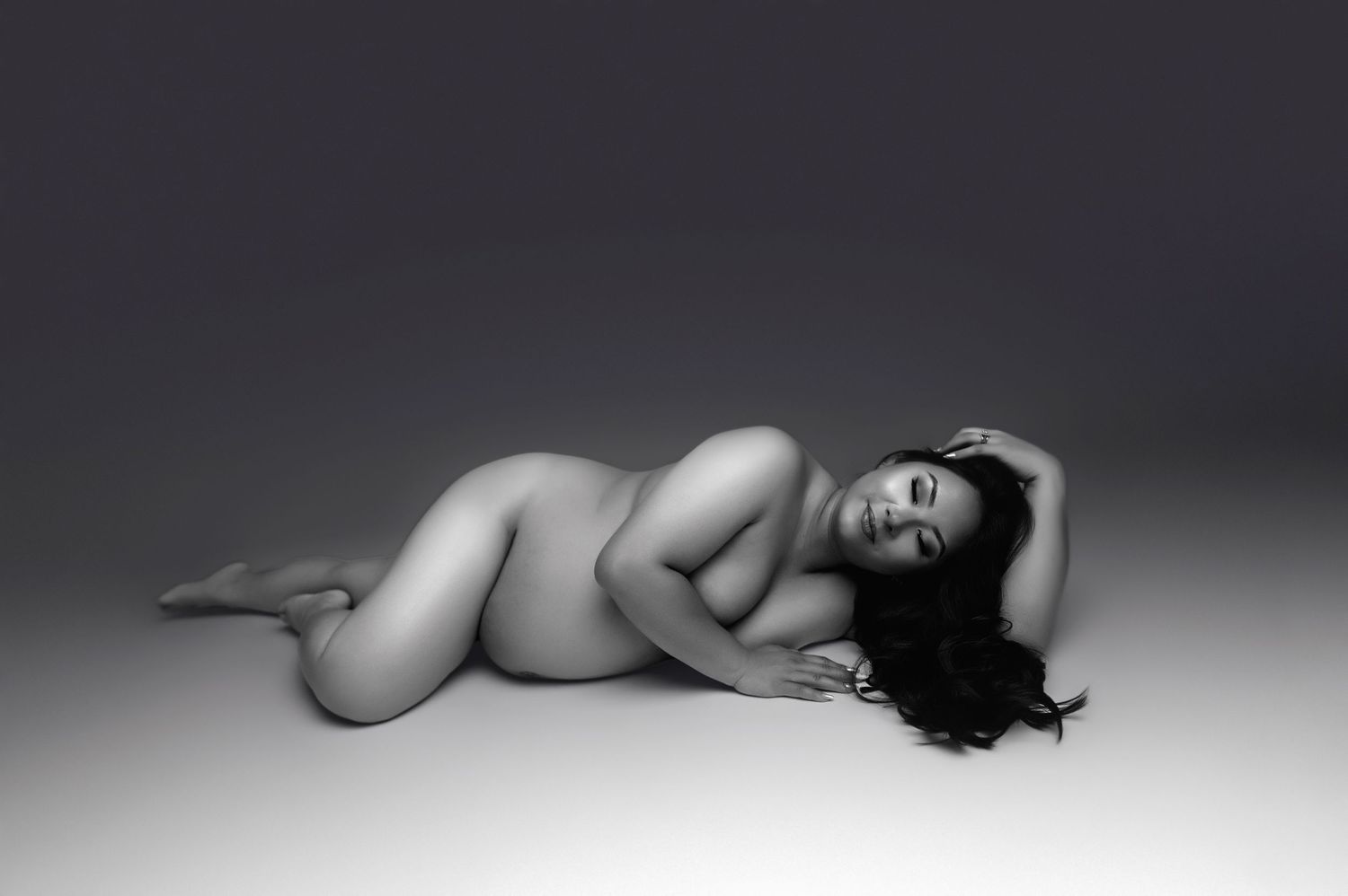 Black and white fine art nude photography of a woman reclining gracefully on a Visalia photography studio floor.
