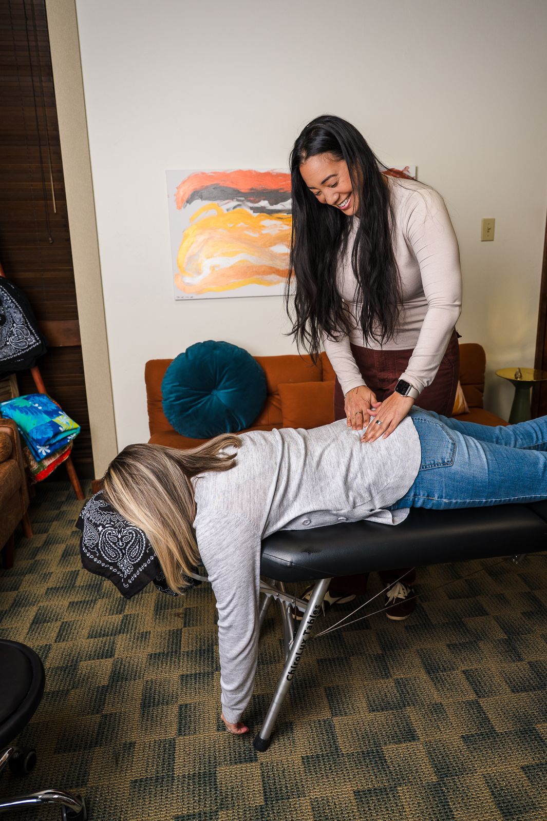 A chiropractor performs a back adjustment on a patient lying face-down on a massage table in a cozy office.