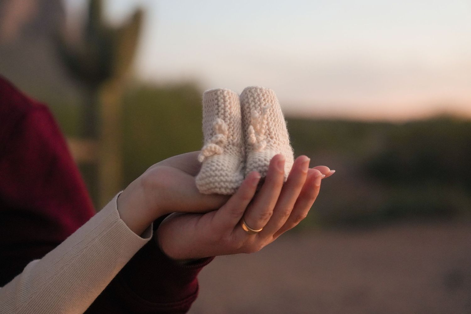 A hand holds a vintage baseball against a blurred sunset background.