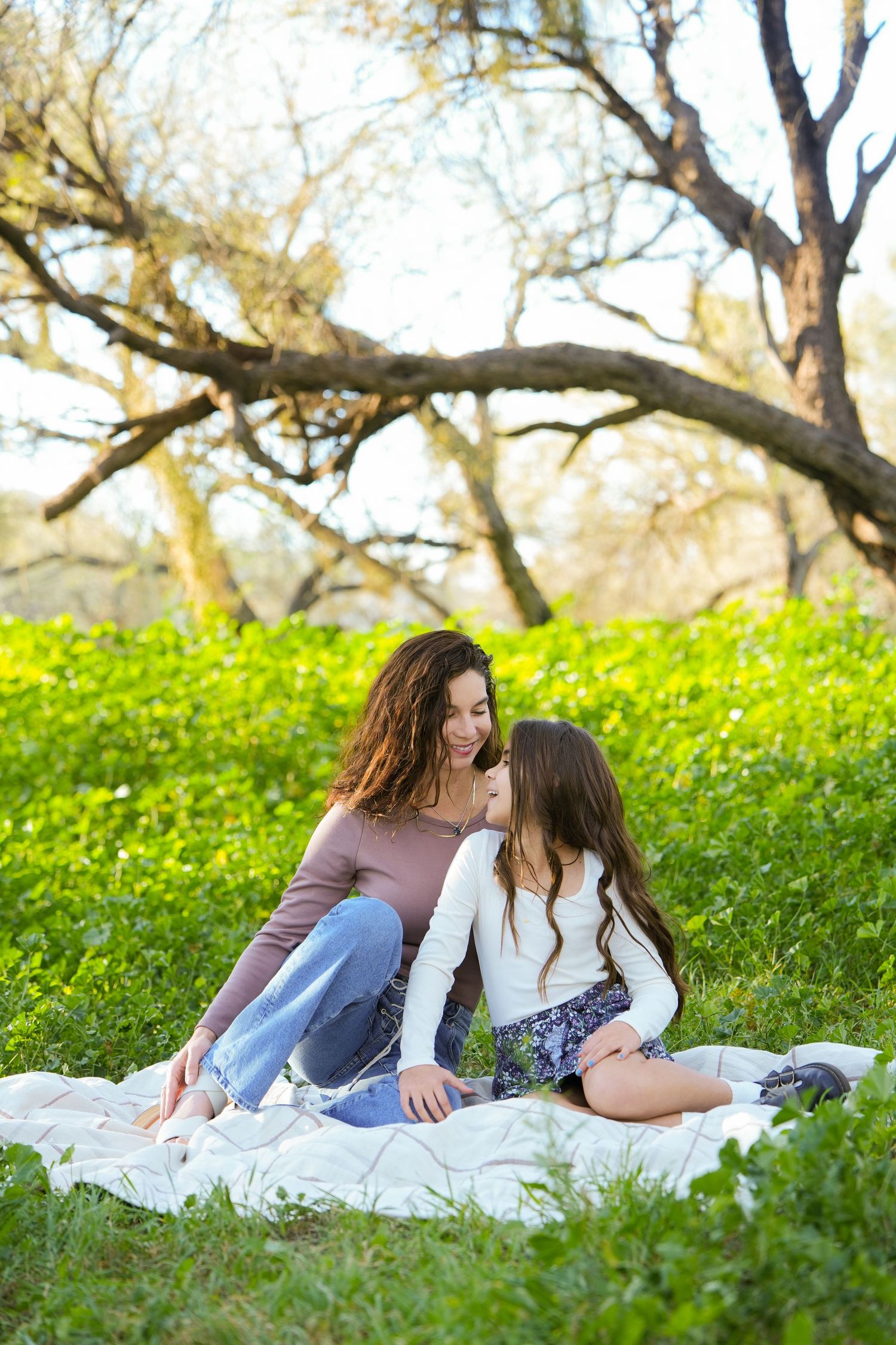 Two people sharing an intimate moment while laying on a white blanket in a spring meadow with yellow wildflowers.