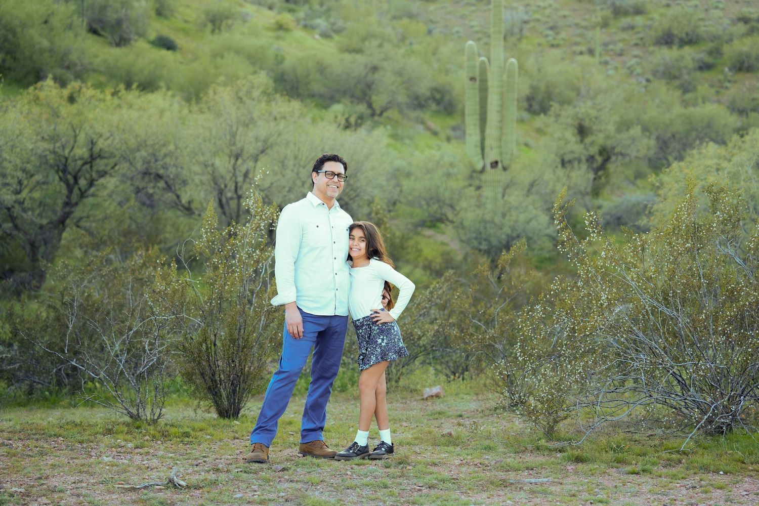 People enjoying a sunny day in a desert landscape with green shrubs and cacti in the background.