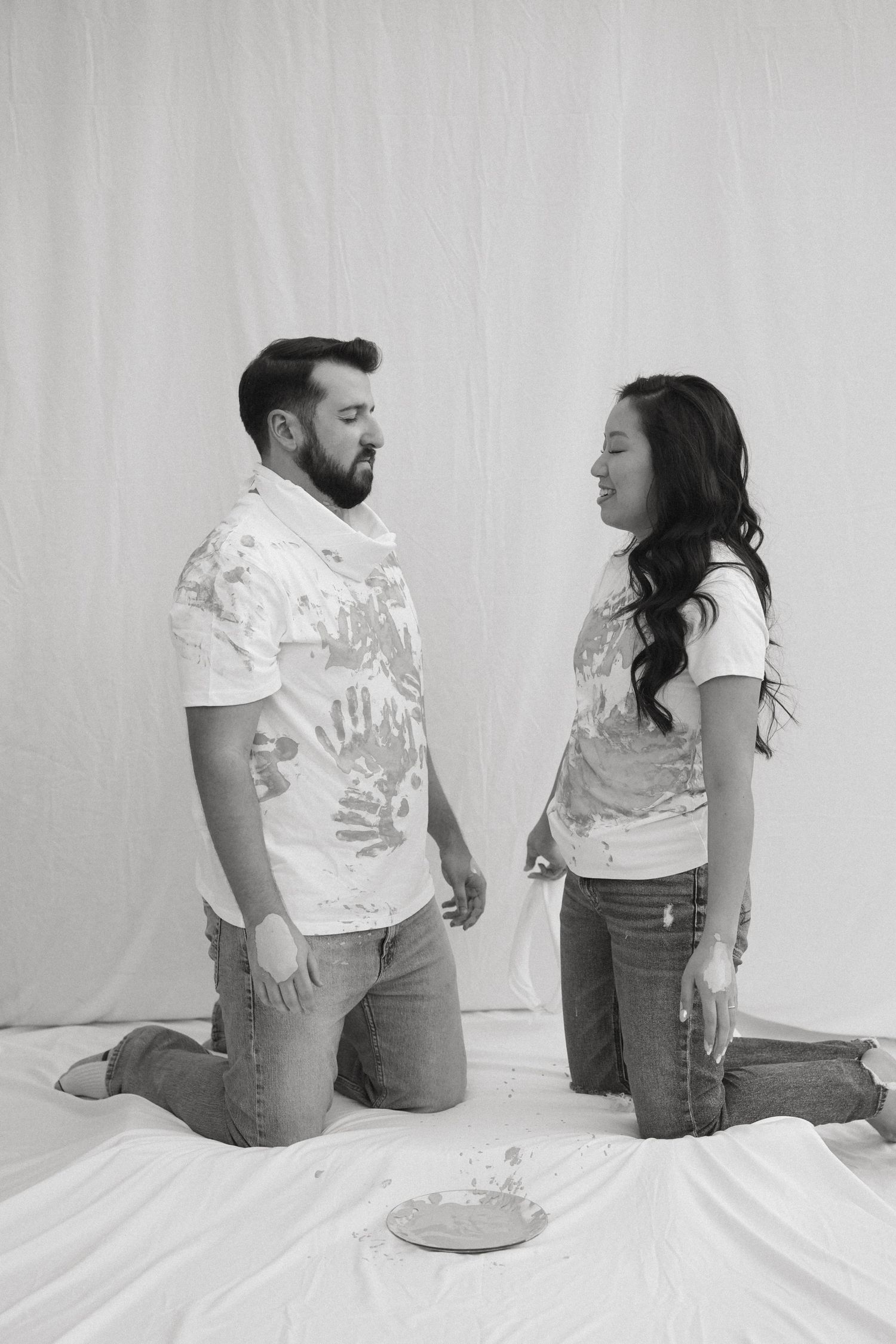A black and white photo sequence showing a couple sitting on a white surface in matching t-shirts and jeans.