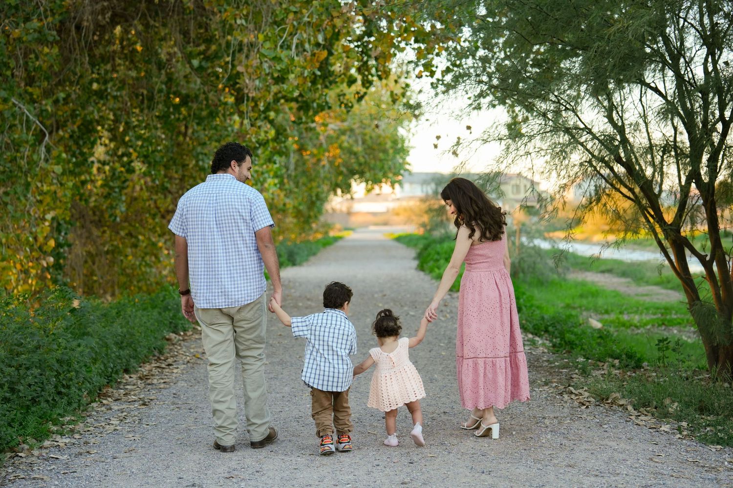 A group walks down a tree-lined path together at sunset creating a silhouetted scene against warm lighting.