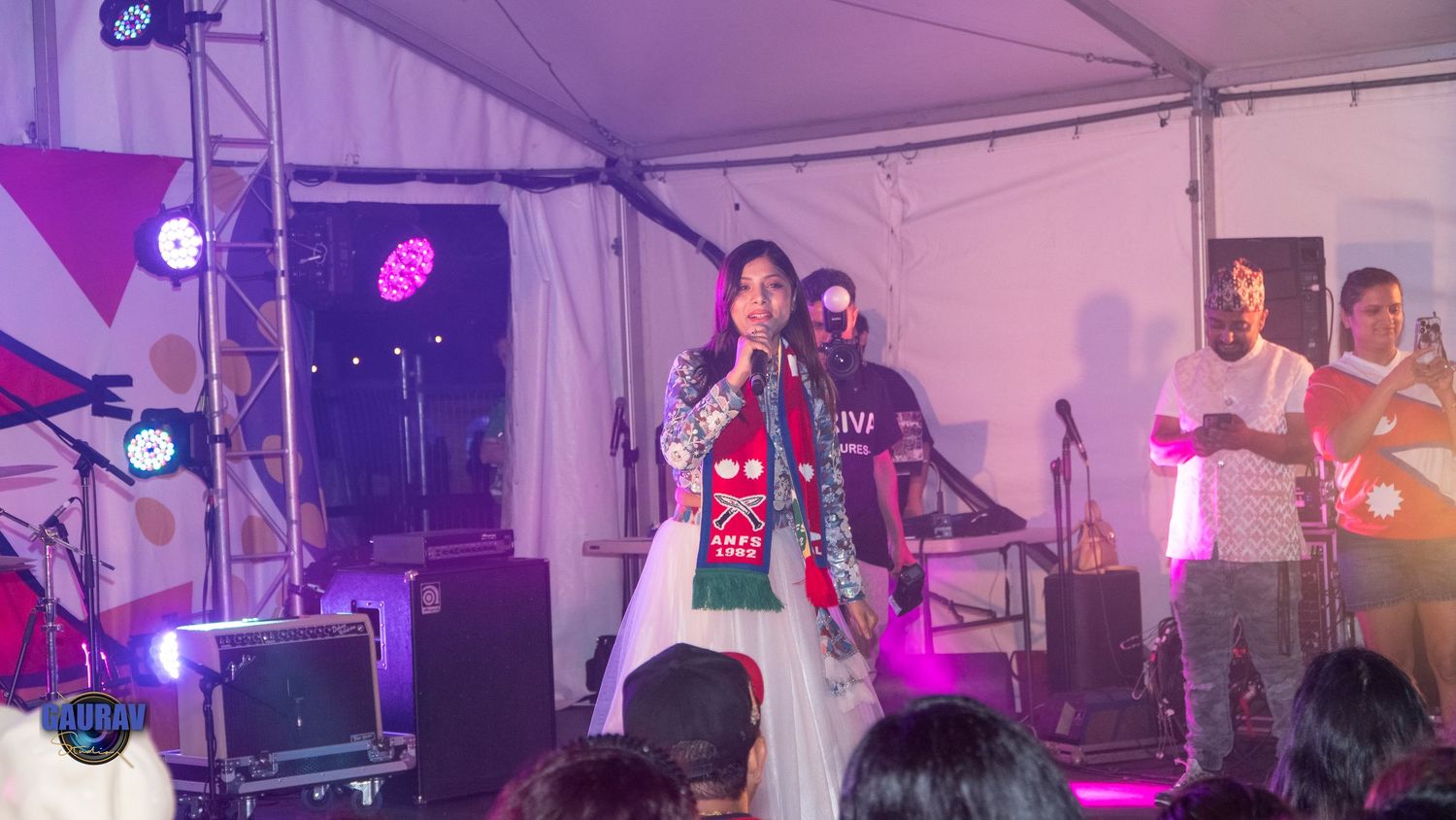 “Performer singing on stage during a live Nepali cultural event with colorful stage lights.”