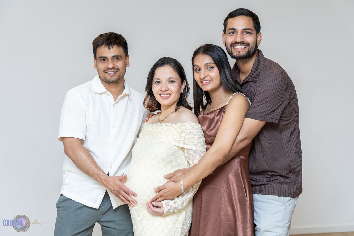 “Group portrait of four people standing together at a baby shower, smiling at the camera.”