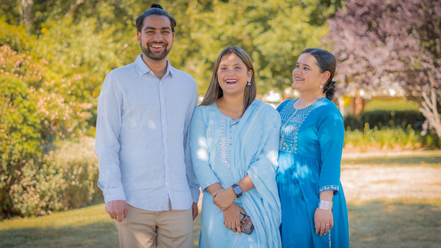 “Family standing together in a park, smiling and posing for a portrait.”