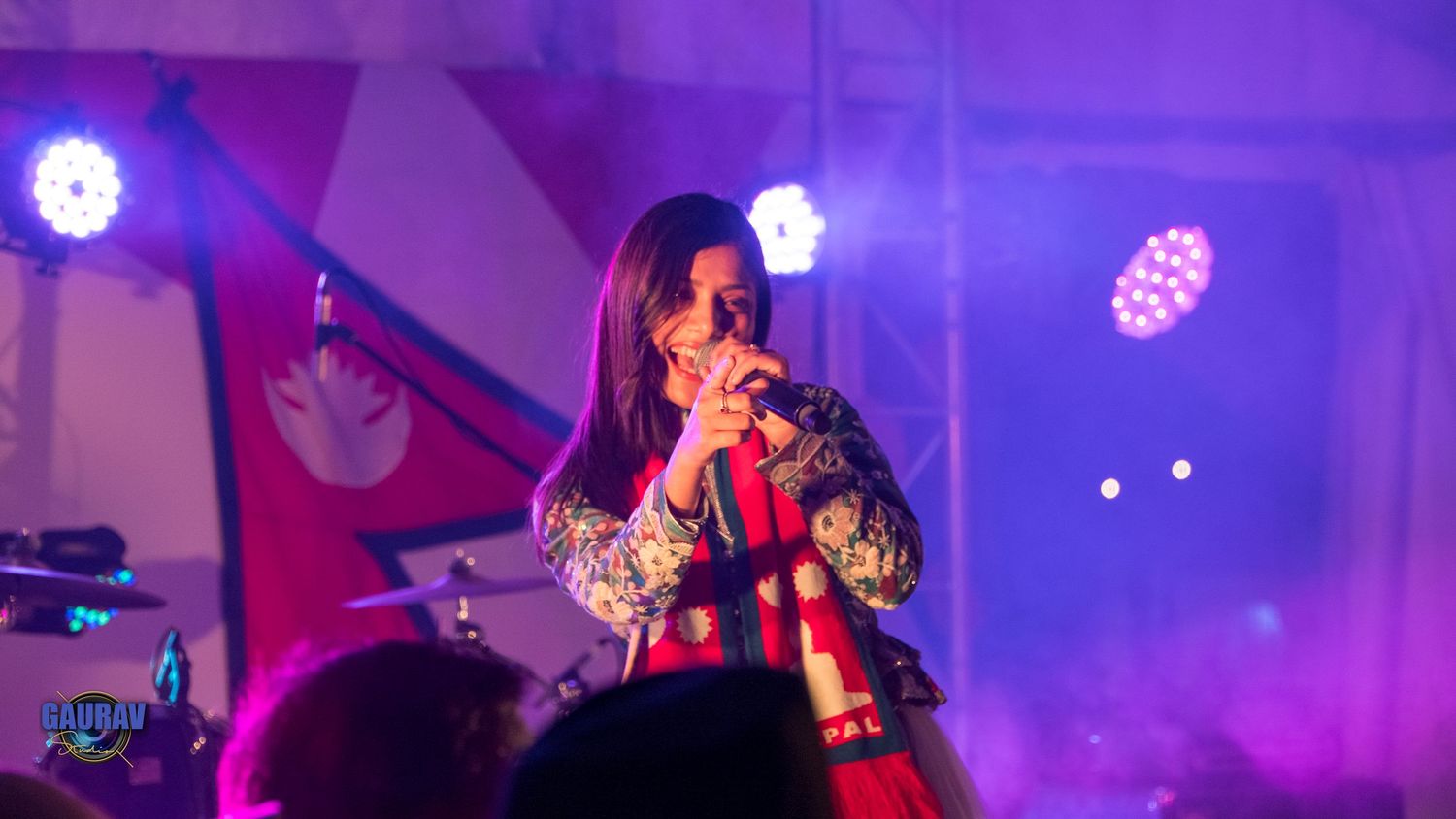 “Female singer performing on stage under purple lights during a live music event.”