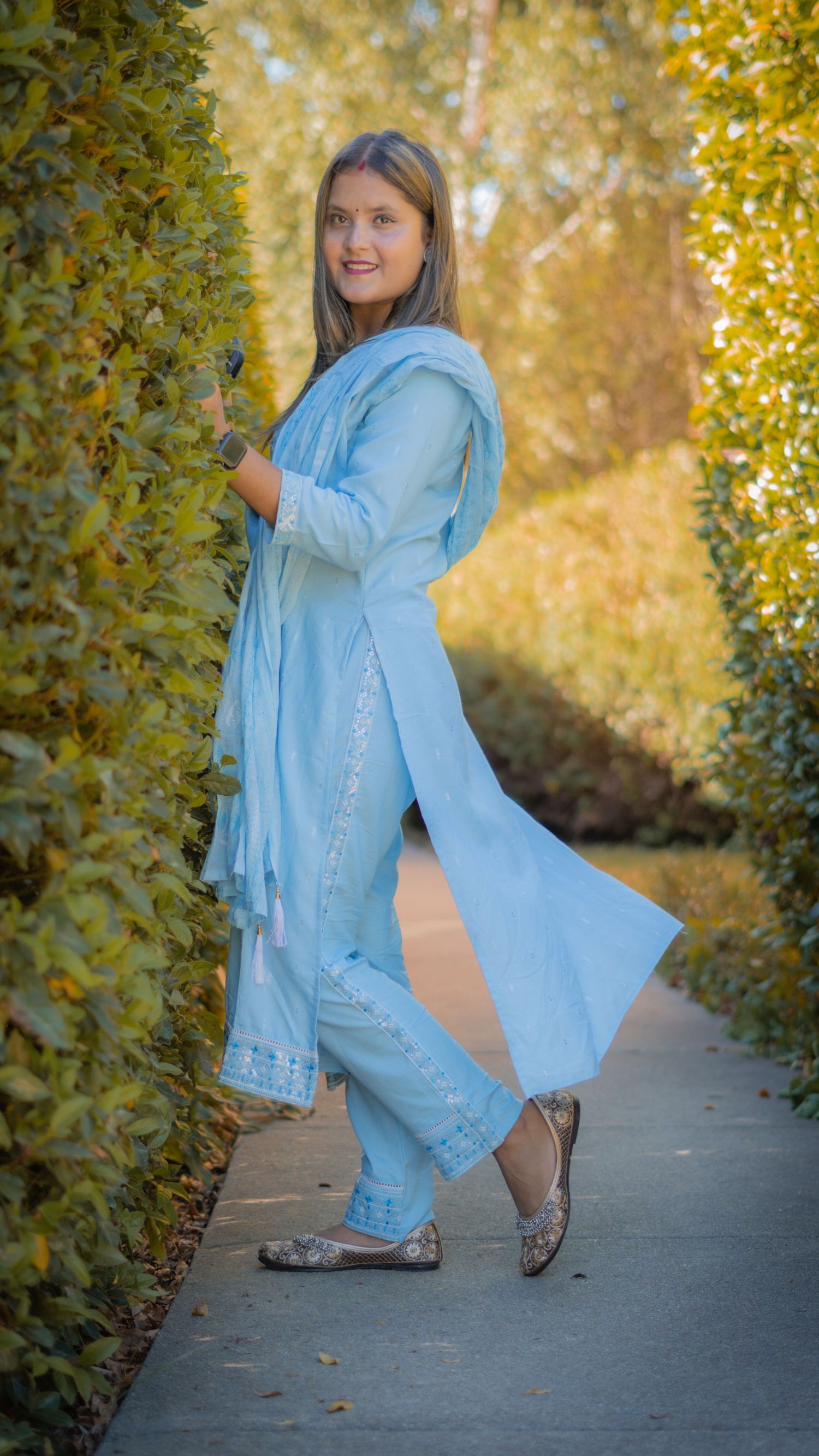 “Portrait of a woman posing in a garden with autumn leaves in the background.”