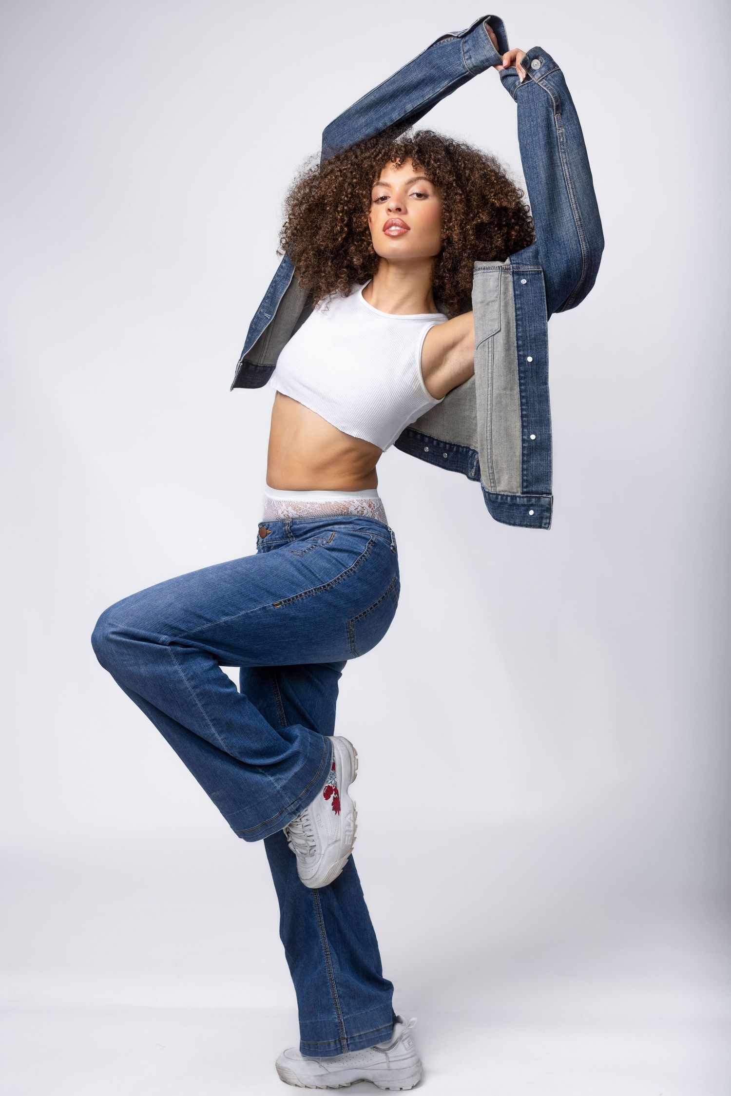 Dynamic fashion poses showing wide leg jeans and white crop top against studio backdrop.