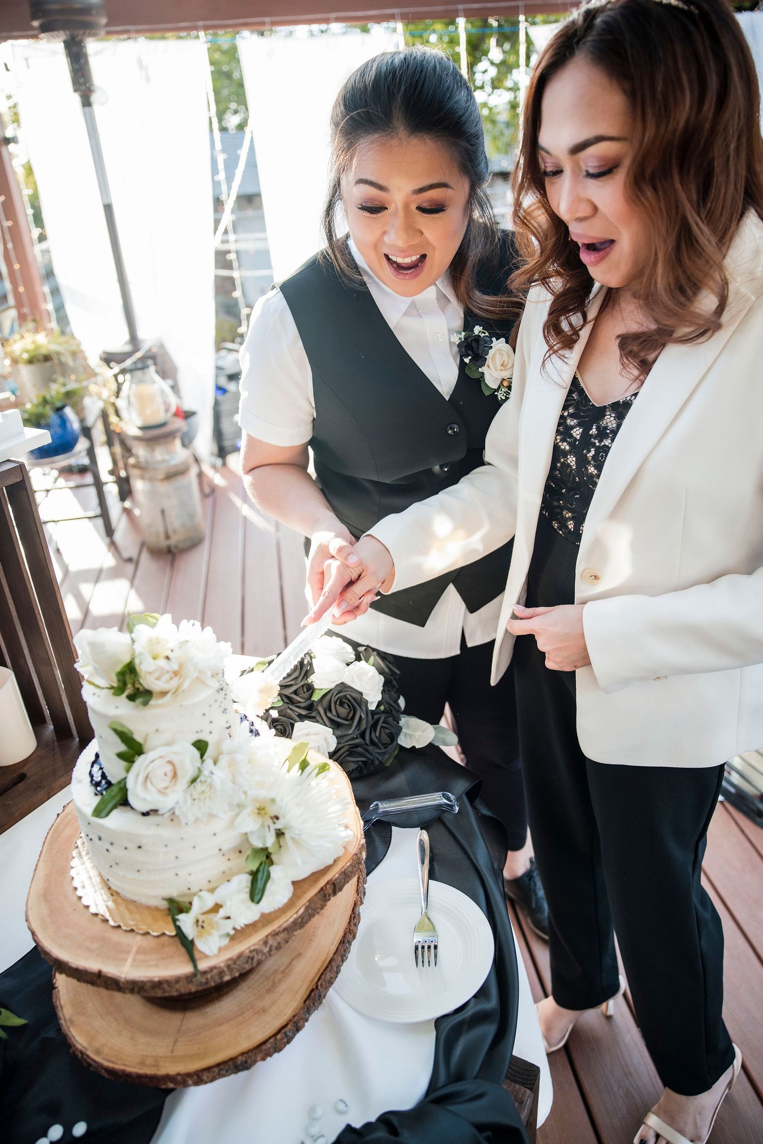 Wedding party enjoys cake and refreshments at rustic wooden table setting.