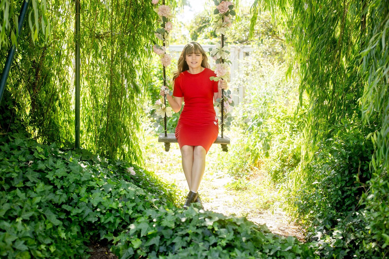 Garden pathway framed by drooping willow trees and lush greenery.