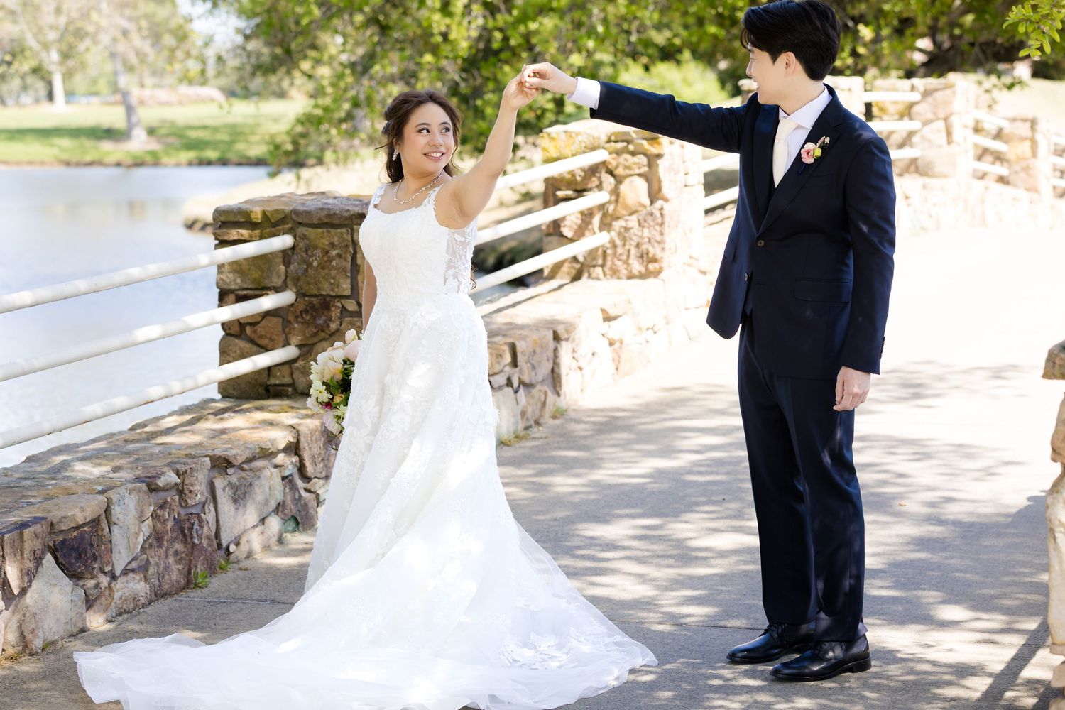 Wedding couple poses together on a rustic stone wall in natural outdoor setting.