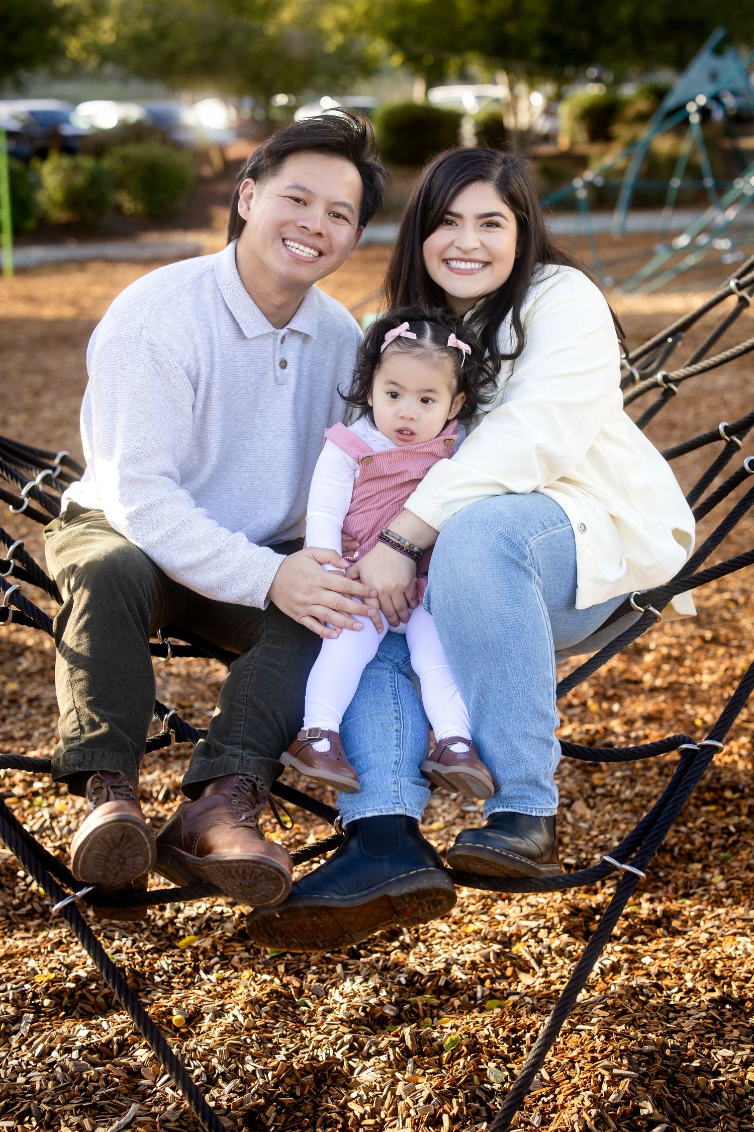 A loving family moment captured on playground equipment with autumn leaves scattered below.