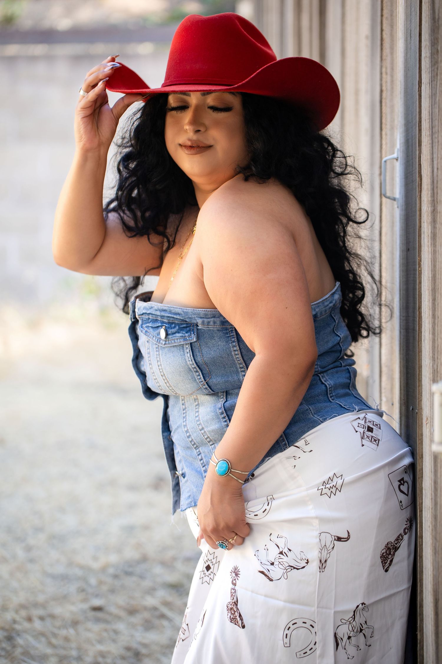 A person in a red hat and denim outfit poses against a light colored wall in an artistic photoshoot sequence.
