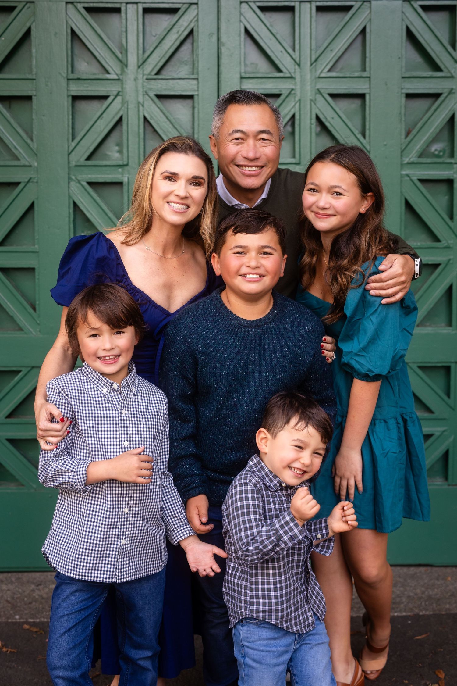 Family group portrait against green geometric patterned backdrop.