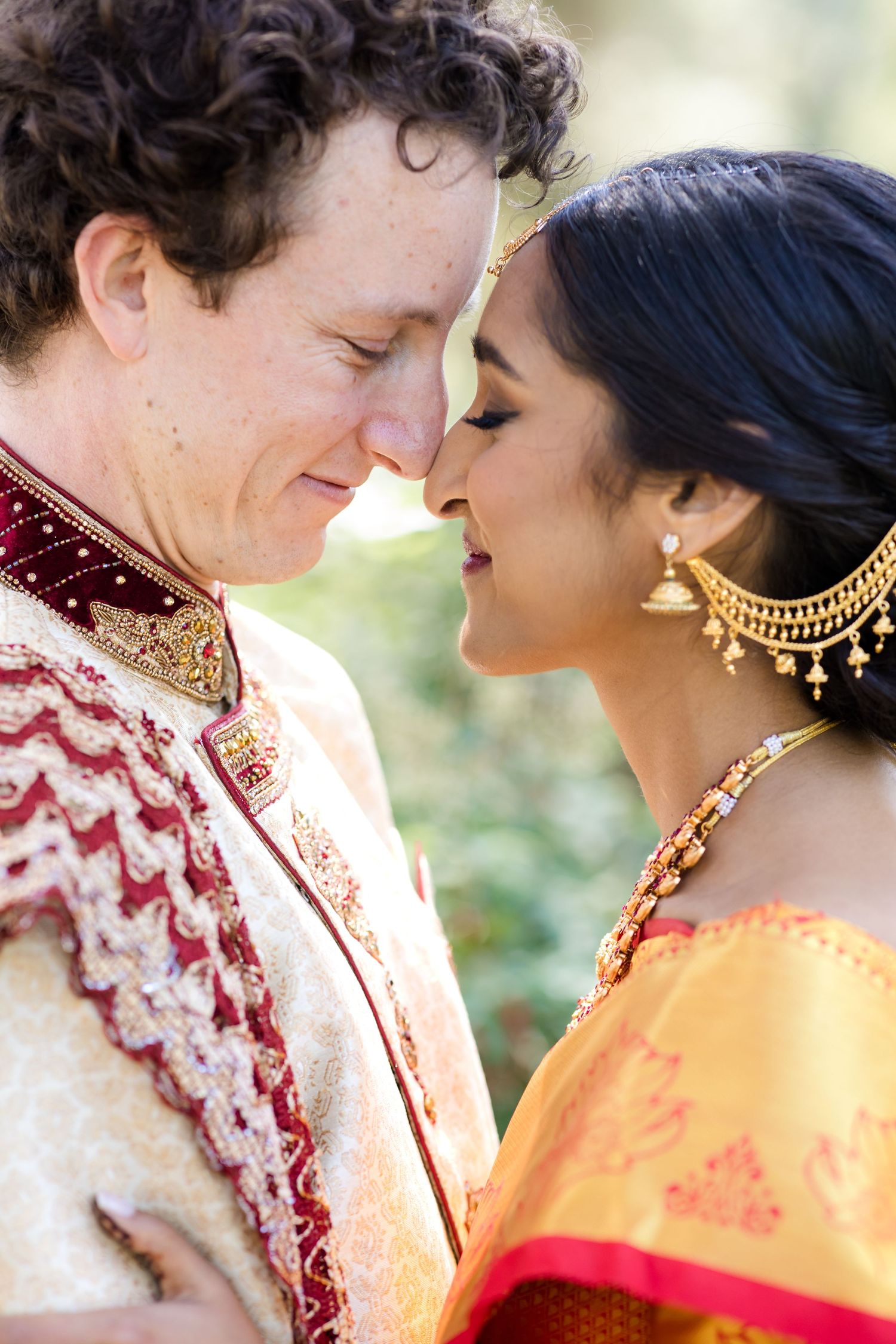 Close-up of couple in Indian wedding attire sharing intimate moment outdoors.