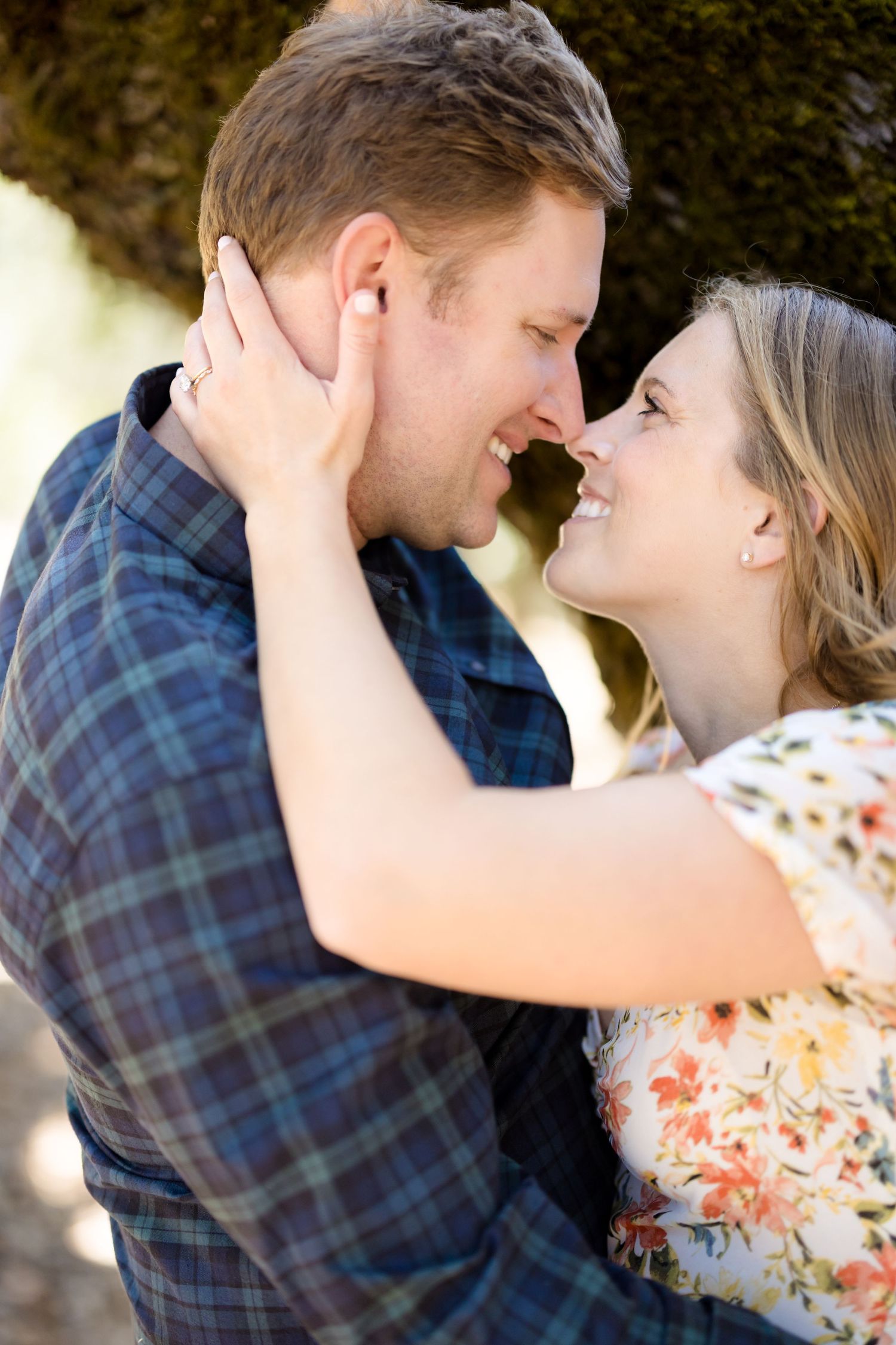 A romantic couple in a plaid shirt and floral dress share tender moments in a series of intimate outdoor photos.