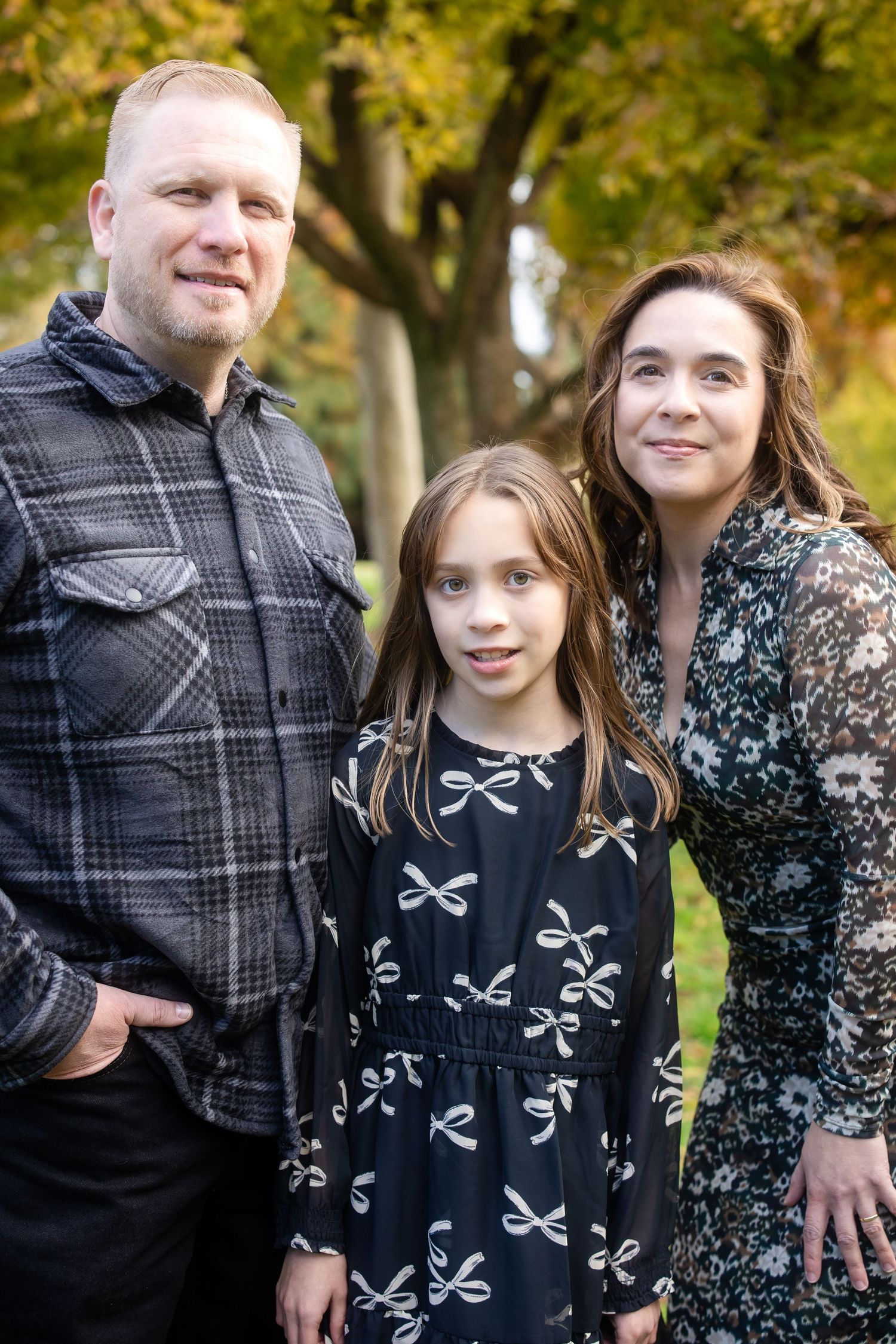 Family members share candid moments during a fall photo session in the park.