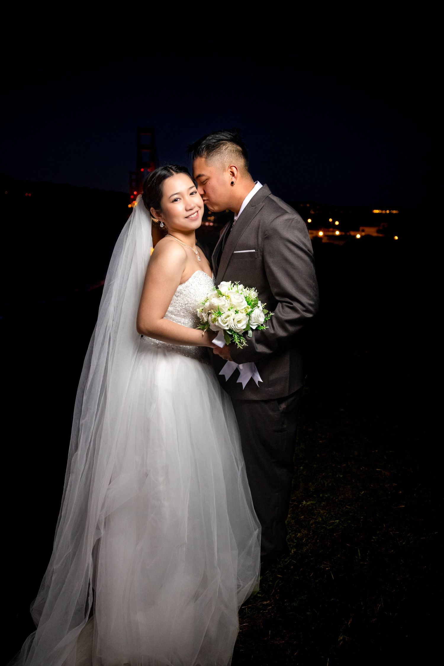 Dramatic nighttime wedding portraits with city lights in background.