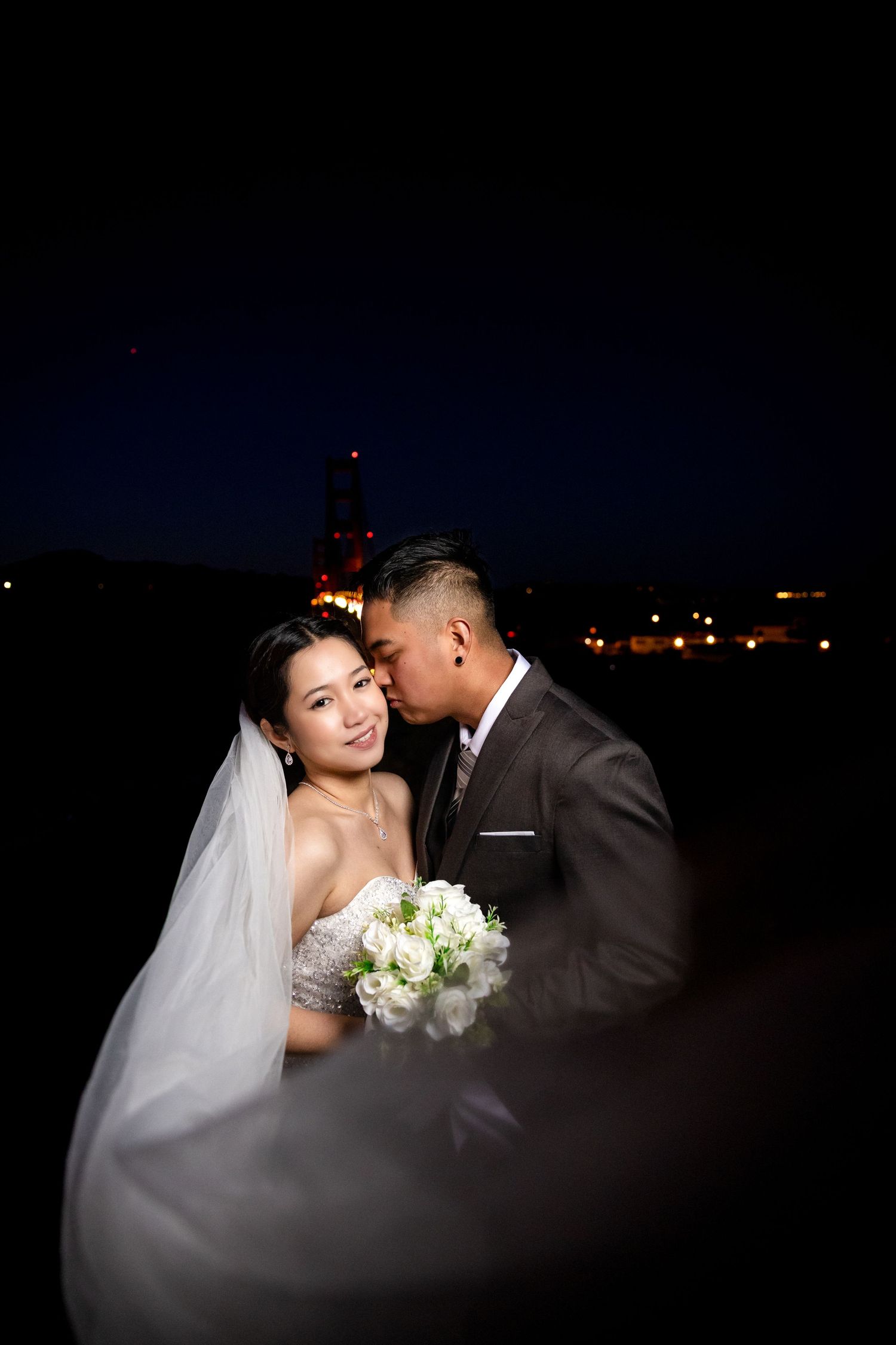 Romantic nighttime wedding portrait with bride holding white bouquet.