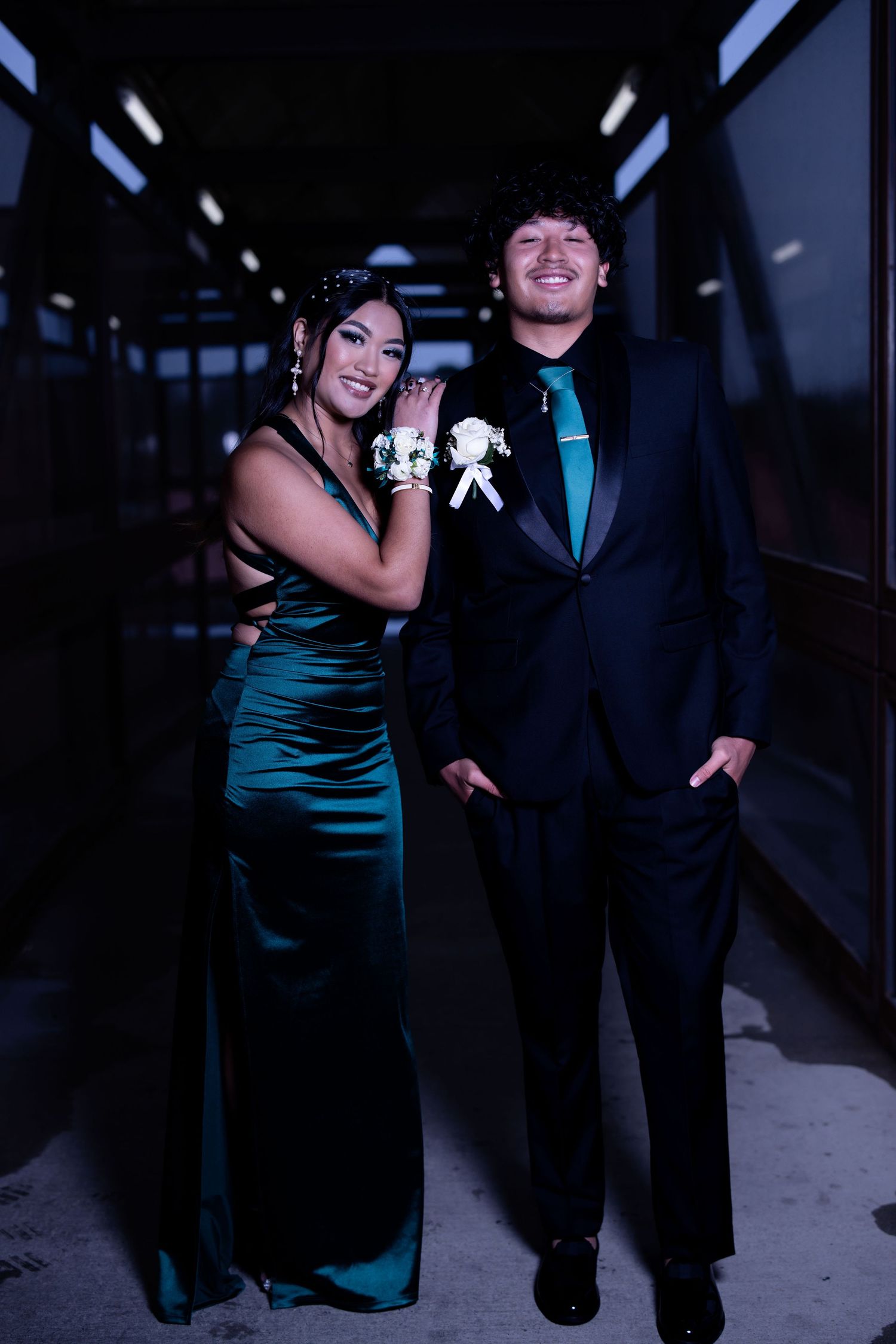 Couple in formal attire posing at night with dramatic lighting.