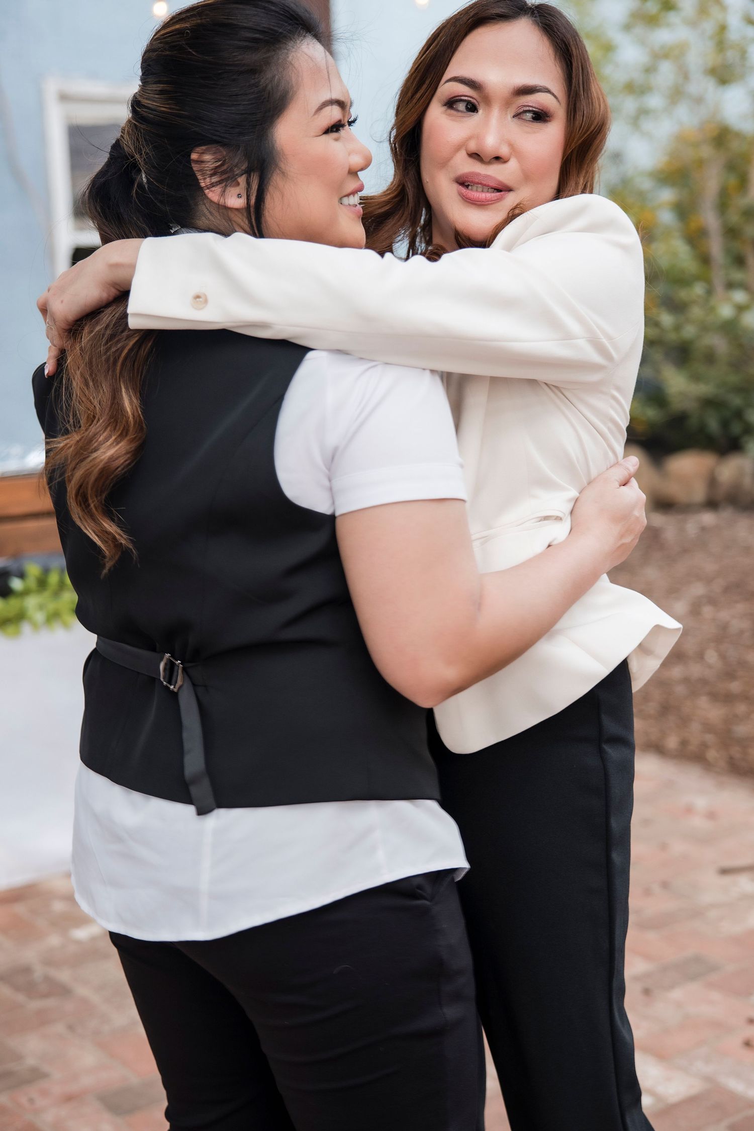 Candid embrace between two people wearing contrasting black and white outfits.