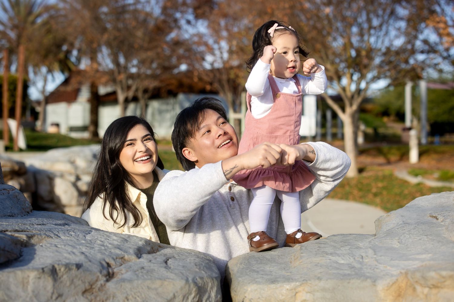 A happy family poses together on a sandy beach with palm trees in the background.