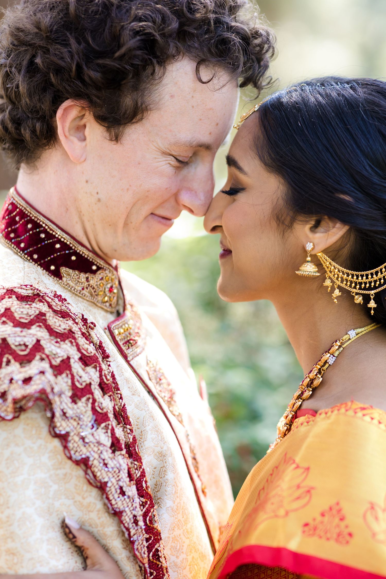 A romantic wedding couple in traditional Indian and Western fusion attire share intimate moments in a garden setting.