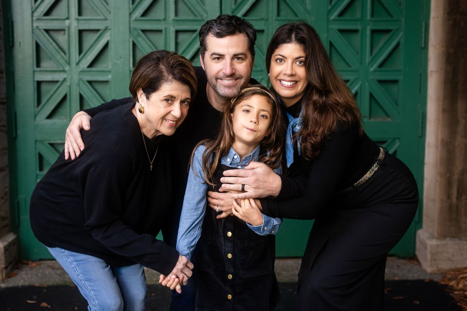 Family portrait against a green geometric patterned wall background.