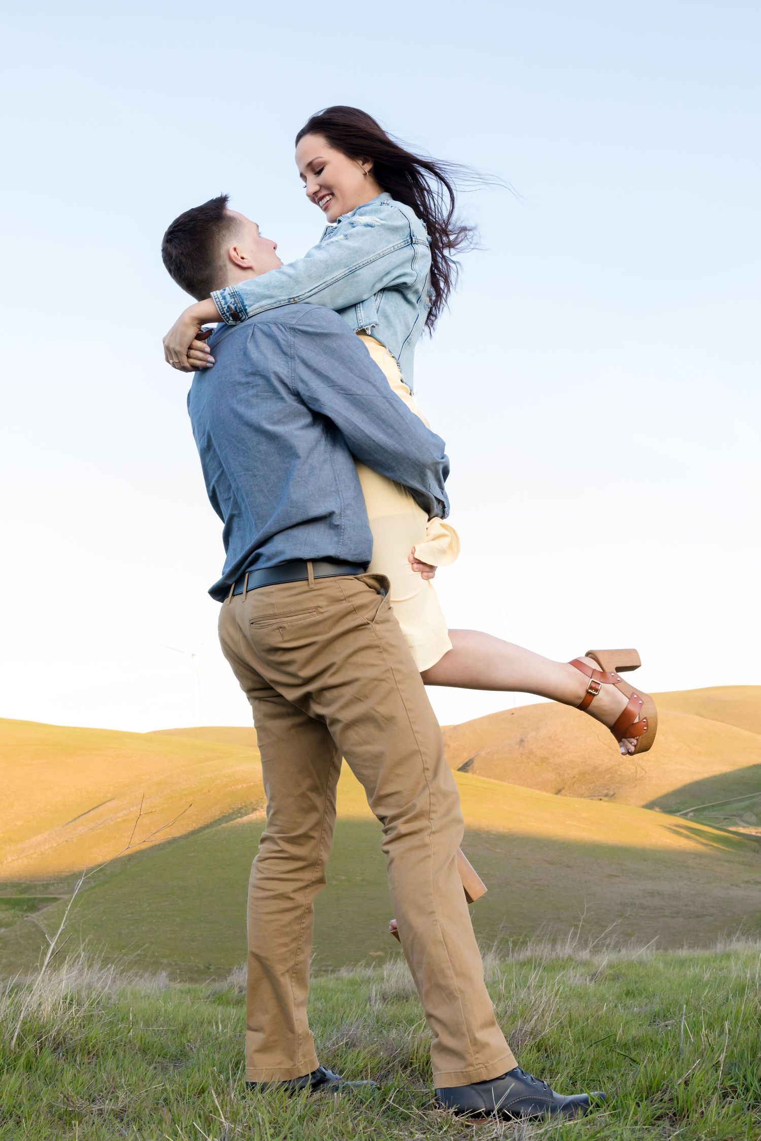 Couple dancing and twirling in green rolling hills during sunset.