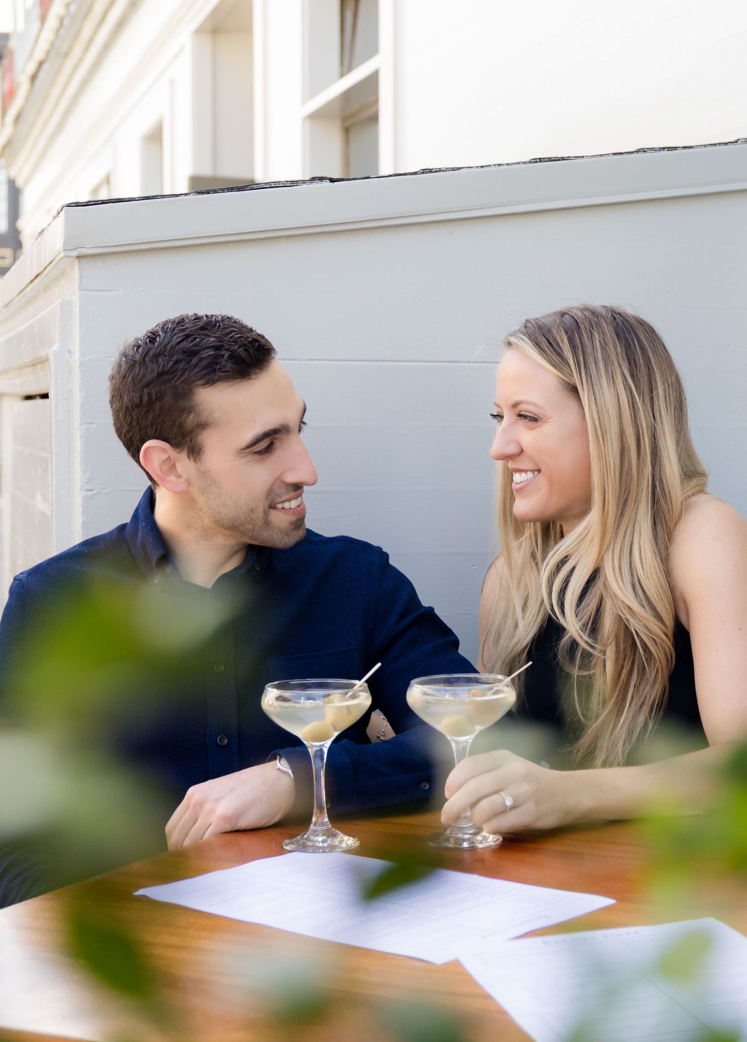 Couple enjoying martinis at outdoor table during romantic date.