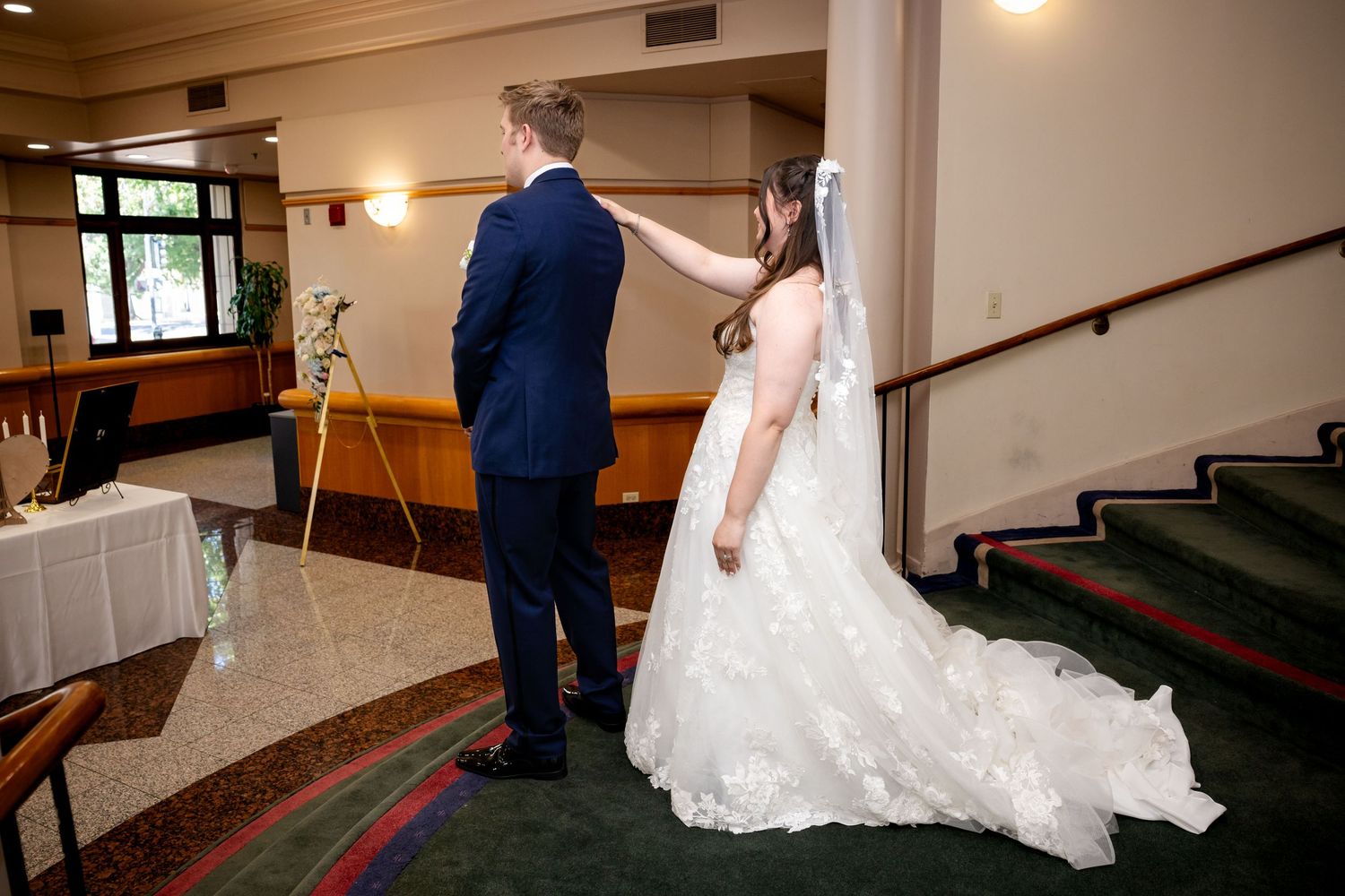 A couple stands in a church aisle during a wedding ceremony with soft lighting and wooden pews.
