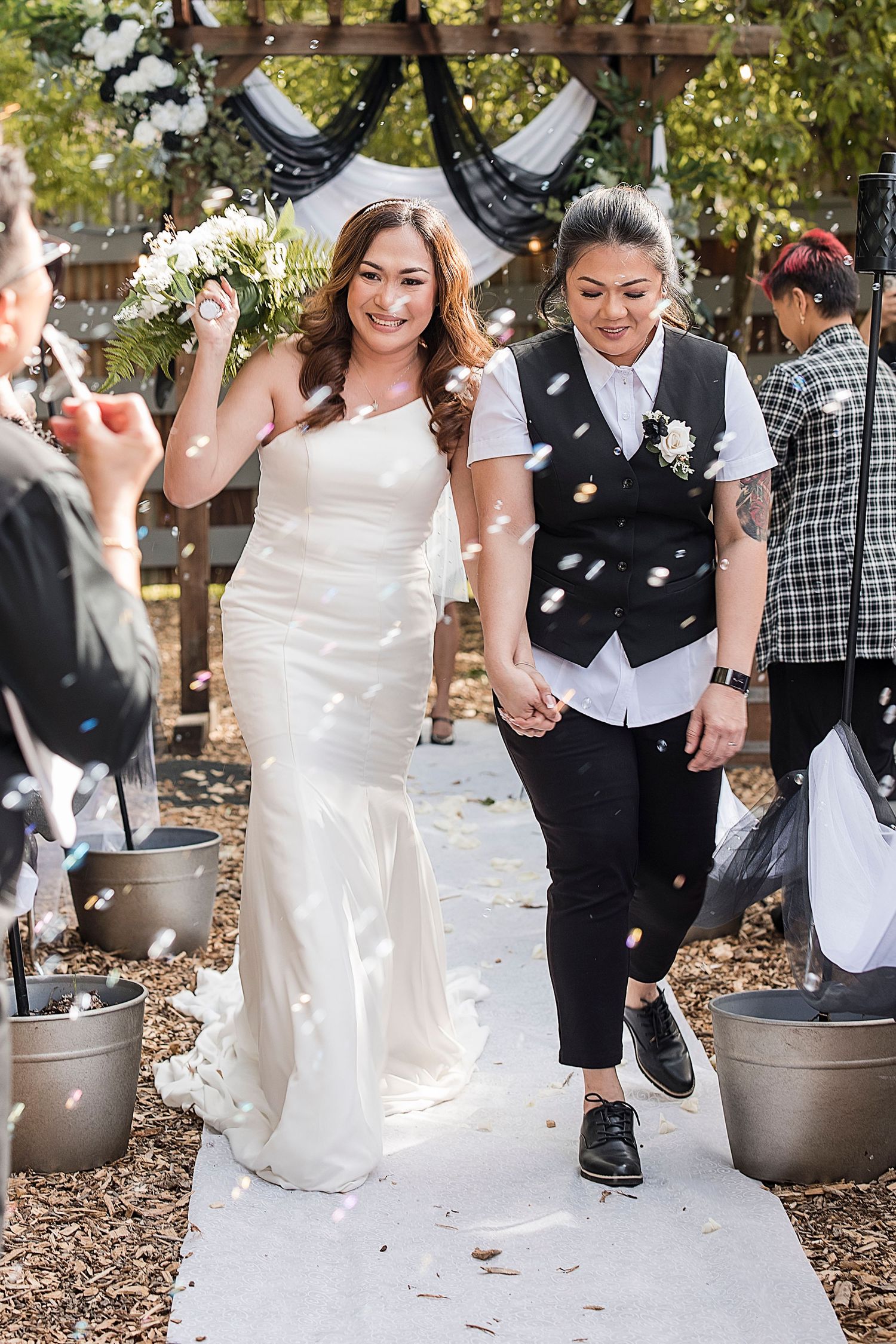 A series of wedding photos showing a couple playfully stomping and bobbing for apples in metal buckets outdoors.