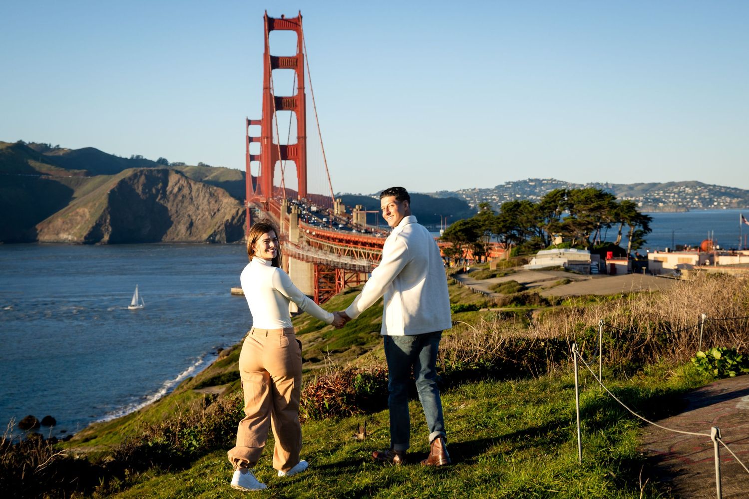 Two people enjoying a scenic moment at Battery Spencer with the Golden Gate Bridge and San Francisco Bay in the background.