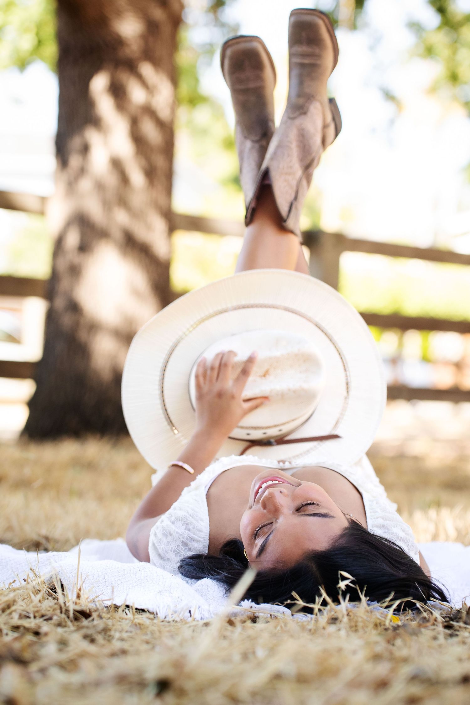 A person in white clothing lies peacefully on autumn leaves in a sun-dappled outdoor setting.