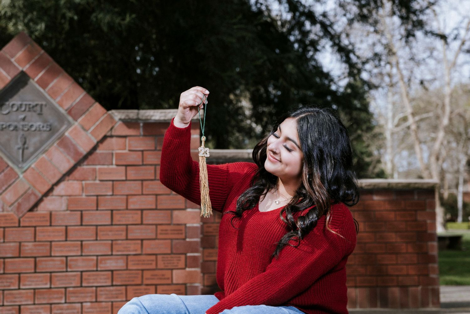 Person in red sweater posing against brick wall outdoors.