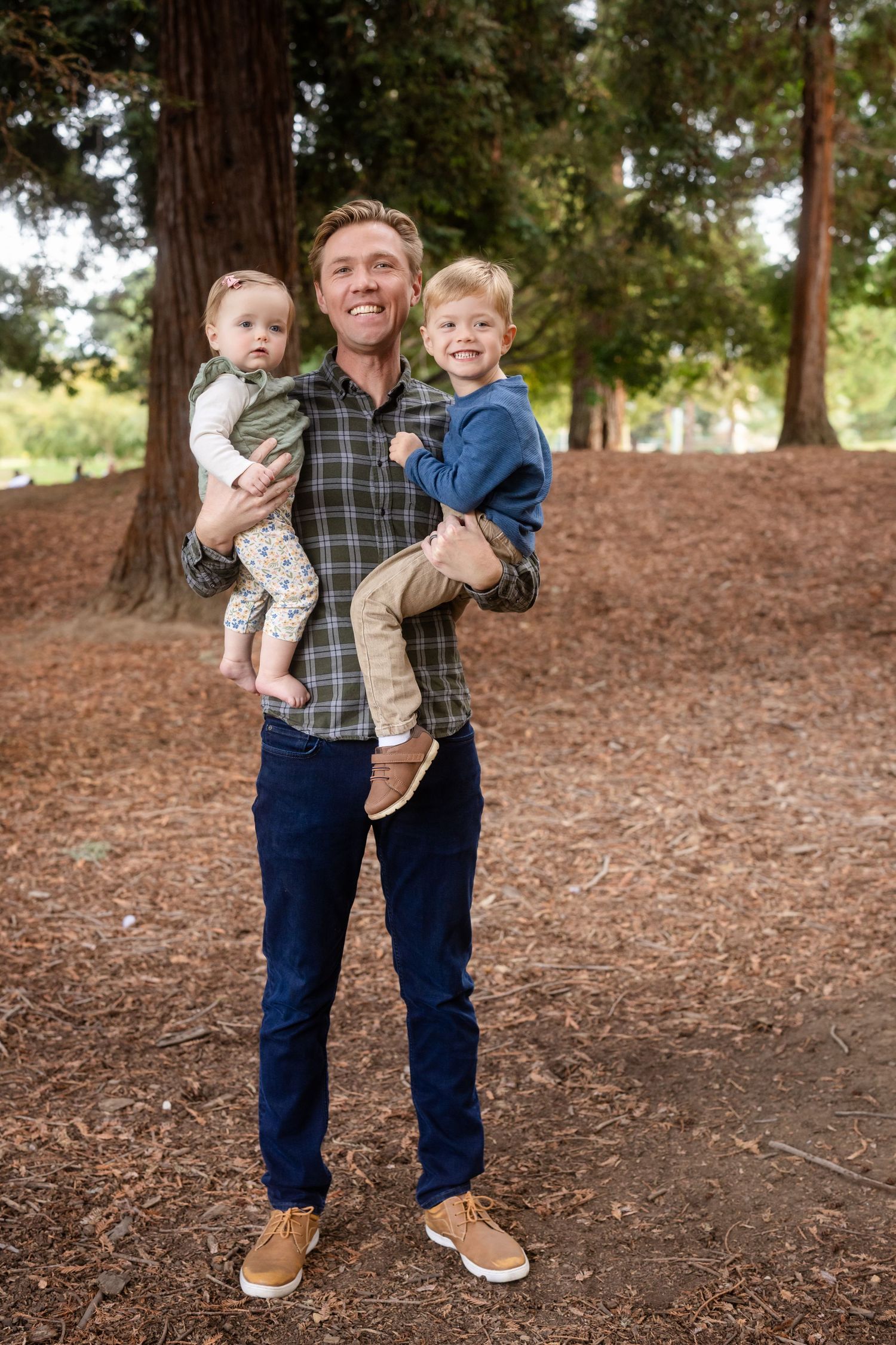 People sharing joyful moments together on ground covered with pine needles in a forest setting.