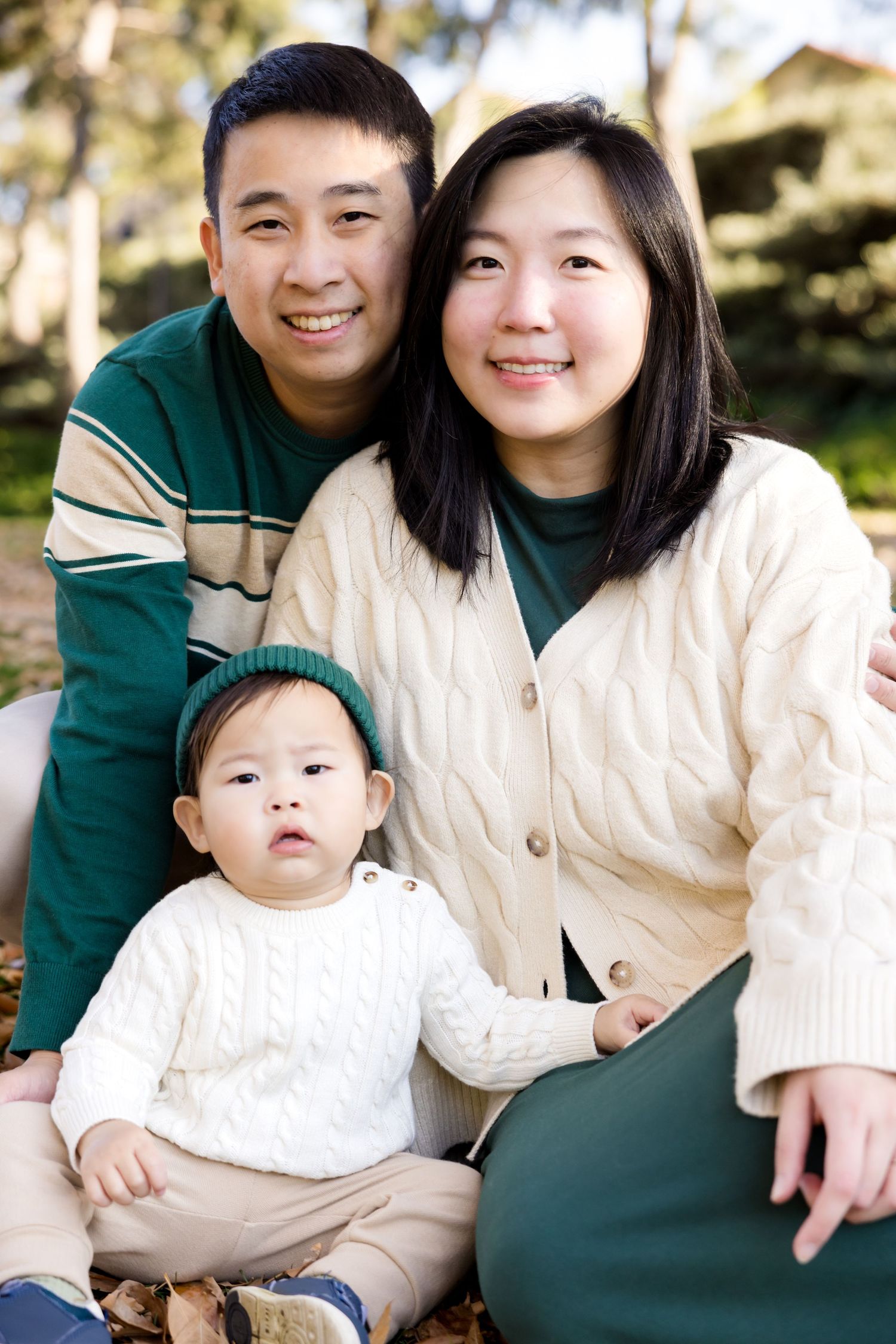 Family in coordinating green and cream outfits pose together outdoors.