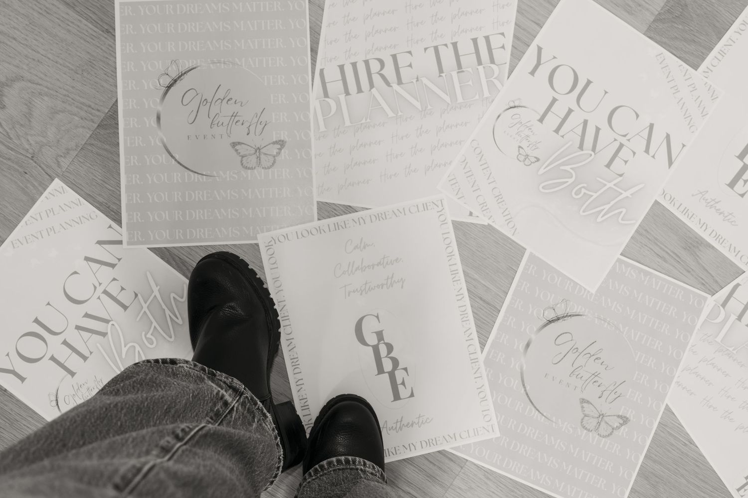Overhead view of motivational printed cards scattered on floor with black boots standing among them.