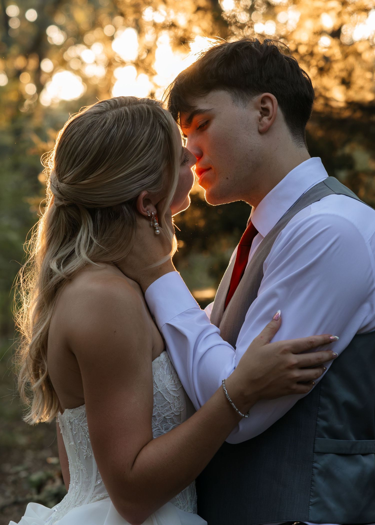 Bride and groom sharing a romantic moment at golden hour sunset in an outdoor woodland wedding venue.