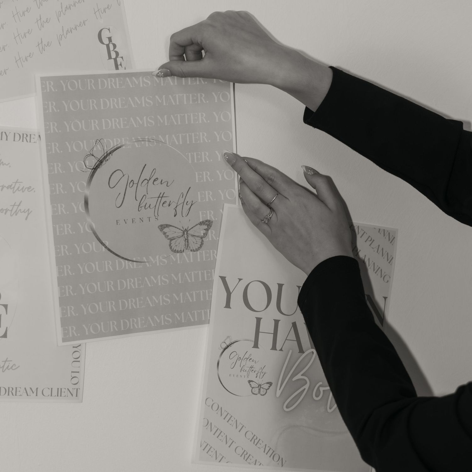 Hands holding branded print materials for Golden Butterfly Events against a white background.